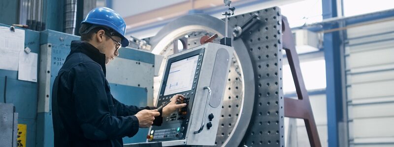 Image of an apprentice working at a computer to calibrate a machine used for manufacturing.